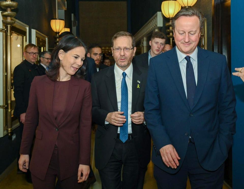 Israeli president Isaac Herzog with David Cameron and German foreign minister Annalena Baerbock (EPA)
