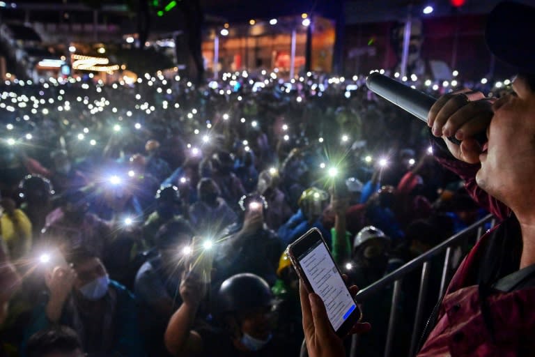 Pro-democracy protesters hold up their mobile phones flashlights as they listen to a speaker during a rally at Bangkok's Victory Monument
