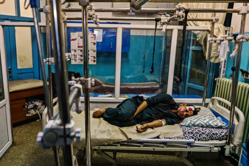 A wounded patient lies in a hospital bed.