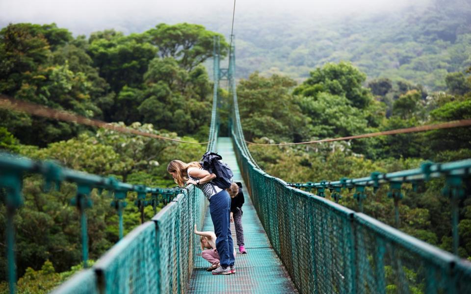 Mother with daughters on hanging bridge - Shutterstock