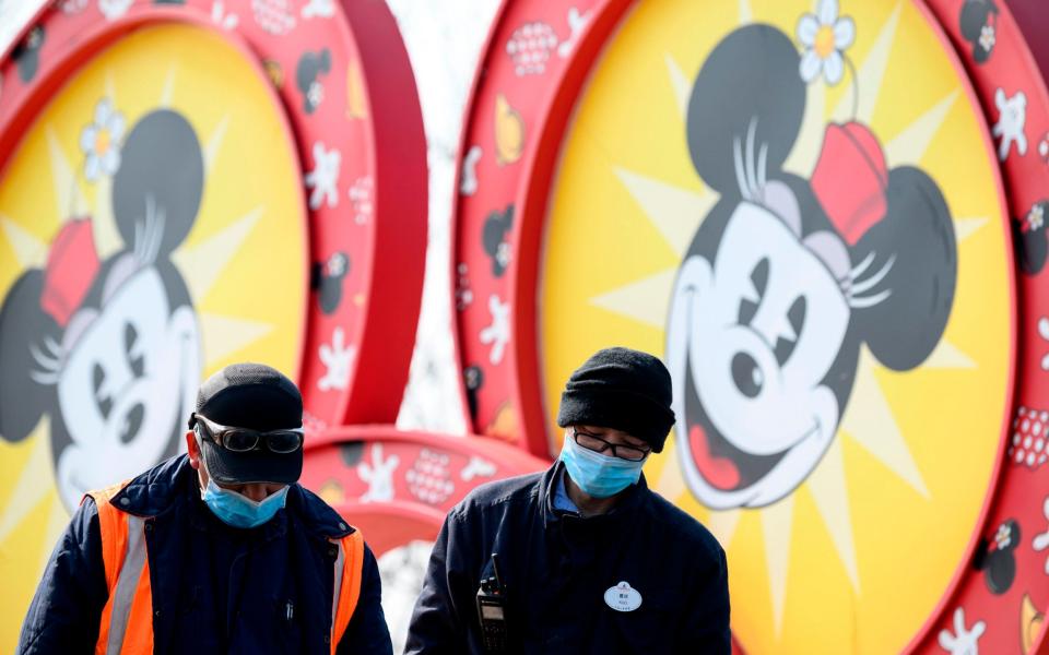 Workers wearing protective facemasks are seen at the Shanghai Disney resort in Shanghai - AFP