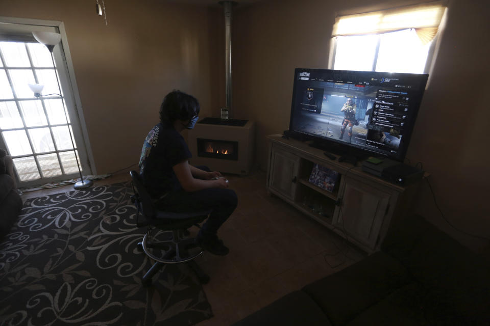 Javin Lujan Lopez, 17, a senior at Pojoaque High School, plays video games at his house on Monday, Feb. 22, 2021, in Española, N.M. He isn’t sure what will happen after graduation. He's considering a welding certificate program at the local community college. He applied to universities in New Mexico and Colorado but feels like the pandemic year didn’t allow him to put his best foot forward. (AP Photo/Cedar Attanasio)