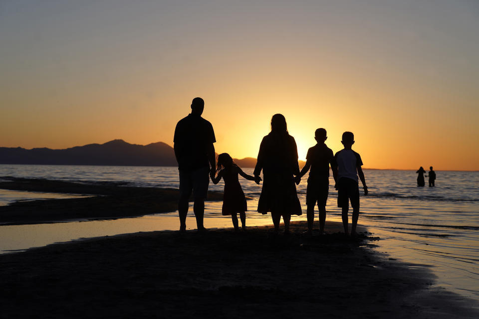 People gather at the receding edge of the Great Salt Lake to watch the sunset on June 13, 2021, near Salt Lake City. The lake has been shrinking for years, and a drought gripping the American West could make this year the worst yet. (AP Photo/Rick Bowmer)