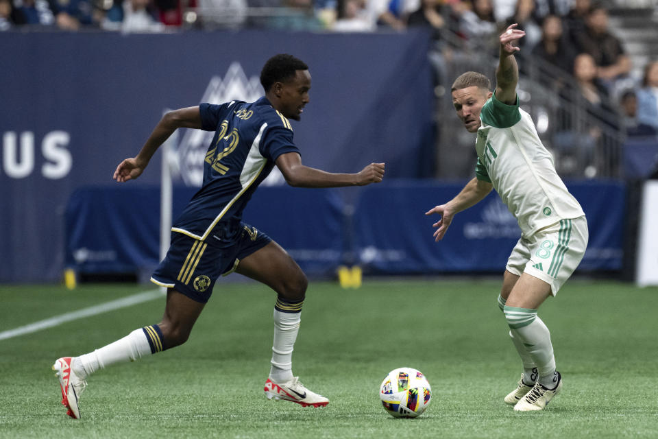 Vancouver Whitecaps' Ali Ahmed, left, runs with the ball as Austin FC's Alexander Ring (8) defends during the first half of an MLS soccer match in Vancouver, British Columbia, on Saturday, May 4, 2024. (Ethan Cairns/The Canadian Press via AP)