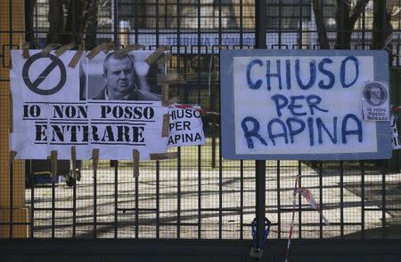 Signs with a picture of Parma soccer team's former president Tommaso Ghirardi reading "I can't go in" (L) and "Closed for robbery" are seen at the entrance of the Ennio Tardini stadium in Parma, March 6, 2015. REUTERS/Stefano Rellandini