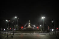 The statue of Italian patriot Giuseppe Garibaldi is lit in the middle of an empty square, in Milan, northern Italy, early Sunday, Oct. 25, 2020. Since the 11 p.m.-5 a.m. curfew took effect last Thursday, people can only move around during those hours for reasons of work, health or necessity. (AP Photo/Luca Bruno)