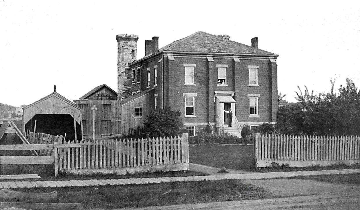 From the early 1850s to 1885, the Oneida County Jail in Utica was located on the west side of Mohawk Street, just north of Eagle Street. The front entrance shown here led to the sheriff’s residence. In the rear, however, stood stone towers guarding a rugged fortress with impenetrable walls where prisoners were held in cells. In the cellar were huge brick ovens where bread was baked for the prisoners and an 80-foot-deep well that provided clear, cold spring water.
