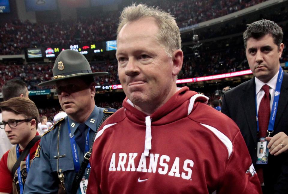 FILE - In this Jan. 4, 2011, file photo, Arkansas coach Bobby Petrino, followed by Arkansas State Police Captain Lance King, left, walks of the field after Arkansas' 31-26 loss to Ohio State in the Sugar Bowl NCAA college football game at the Louisiana Superdome in New Orleans. Scandal-driven offseason coaching changes have become somewhat common in college football. Petrino was fired April 11, 2012, for lying to school officials about his relationship with a woman who was involved in a motorcycle accident with him. (AP Photo/Gerald Herbert, File)