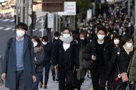 FILE - In this Feb. 20, 2020, photo, people wear masks as they commute during the morning rush hour, in Chuo district in Tokyo. Japan's Prime Minister Shinzo Abe says new measures like companies letting their employees work from home and hospitals expanding their capacity to treat many patients will determine if Japan could control its coronavirus outbreak. (AP Photo/Kiichiro Sato, File)