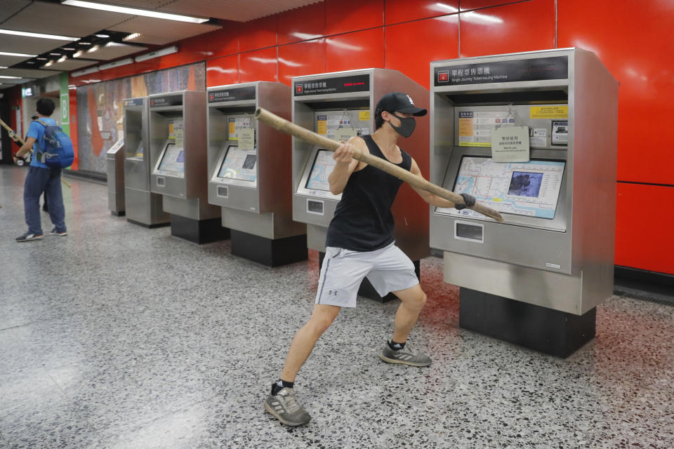 A protester destroys a ticketing machine during a protest in Mong Kok, Hong Kong on Friday, Sept. 6, 2019. The ratings agency Fitch on Friday cut Hong Kong's credit rating and warned that conflict with anti-government protesters was hurting the image of its business climate. (AP Photo/Kin Cheung)