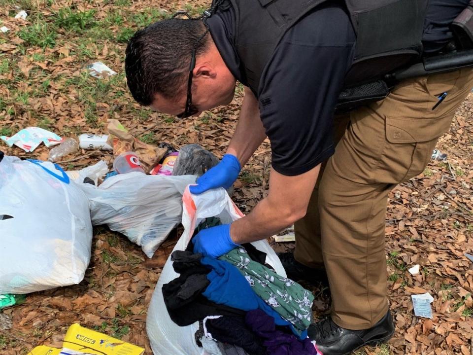 A Spartanburg County litter control officer examines a bag of trash dumped on Robbs Avenue near Asheville Highway and Interstate 85.