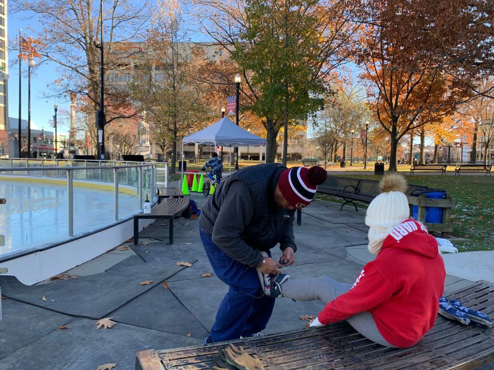 Kasey Moore, 8, gets her skates laced up by her dad, Kyle Moore, at opening of the Worcester Common Oval outdoor ice rink on Saturday.