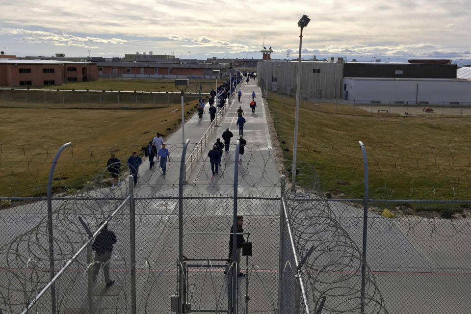 FILE - In this Jan. 30, 2018, file photo, inmates walk across the grounds of the Idaho State Correctional Institution in Kuna, Idaho. A federal judge says the IRS can't keep withholding coronavirus relief payments from incarcerated people, potentially clearing the way for at least 80,000 checks totaling more than $100 million to be sent to people behind bars across the United States. The ruling from U.S. District Judge Phyllis J. Hamilton late last month gives the IRS until Oct. 2, 2020, to reconsider the payments for those who were denied or had their money intercepted solely because of their incarceration. (AP Photo/Rebecca Boone, File)