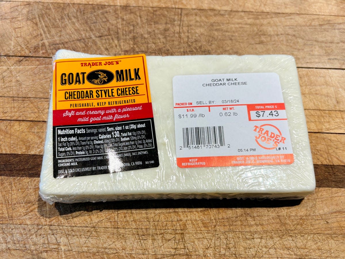 A rectangular block of white cheese with a yellow and red label reading "goat-milk cheddar-style cheese"