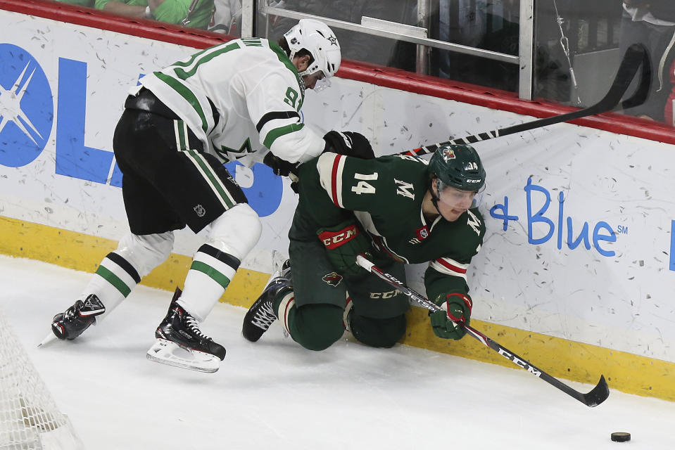 Minnesota Wild's Joel Eriksson Ek, of Sweden, reaches for the puck against the defense of Dallas Stars' Tyler Seguin in the first period of an NHL hockey game Saturday, Jan. 18, 2020, in St. Paul, Minn. (AP Photo/Stacy Bengs)