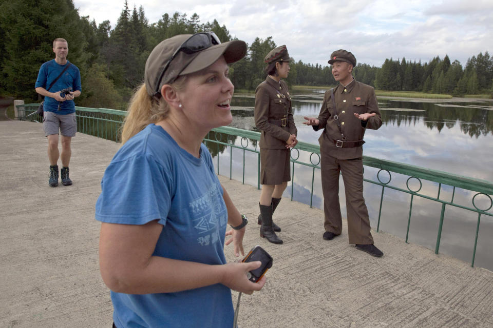 In this Friday, Aug. 17, 2018, photo, Sinead of Australia, center, and Tarjei Naess Skrede of Norway, left, stand near North Korean guides during a hiking trip organized by Roger Shepherd of Hike Korea, unseen, which included a tour of a monument near Mount Paektu in North Korea. Hoping to open up a side of North Korea rarely seen by outsiders, Shepherd, a New Zealander who has extensive experience climbing the mountains of North and South Korea is leading the first group of foreign tourists allowed to trek off road and camp out under the stars on Mount Paektu, a huge volcano that straddles the border that separates China and North Korea. (AP Photo/Ng Han Guan)
