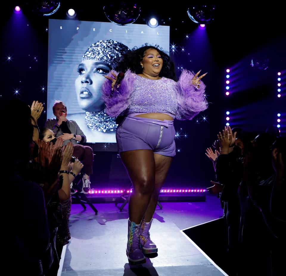 Lizzo performs at the iHeartRadio Album Release Party in a purple outfit