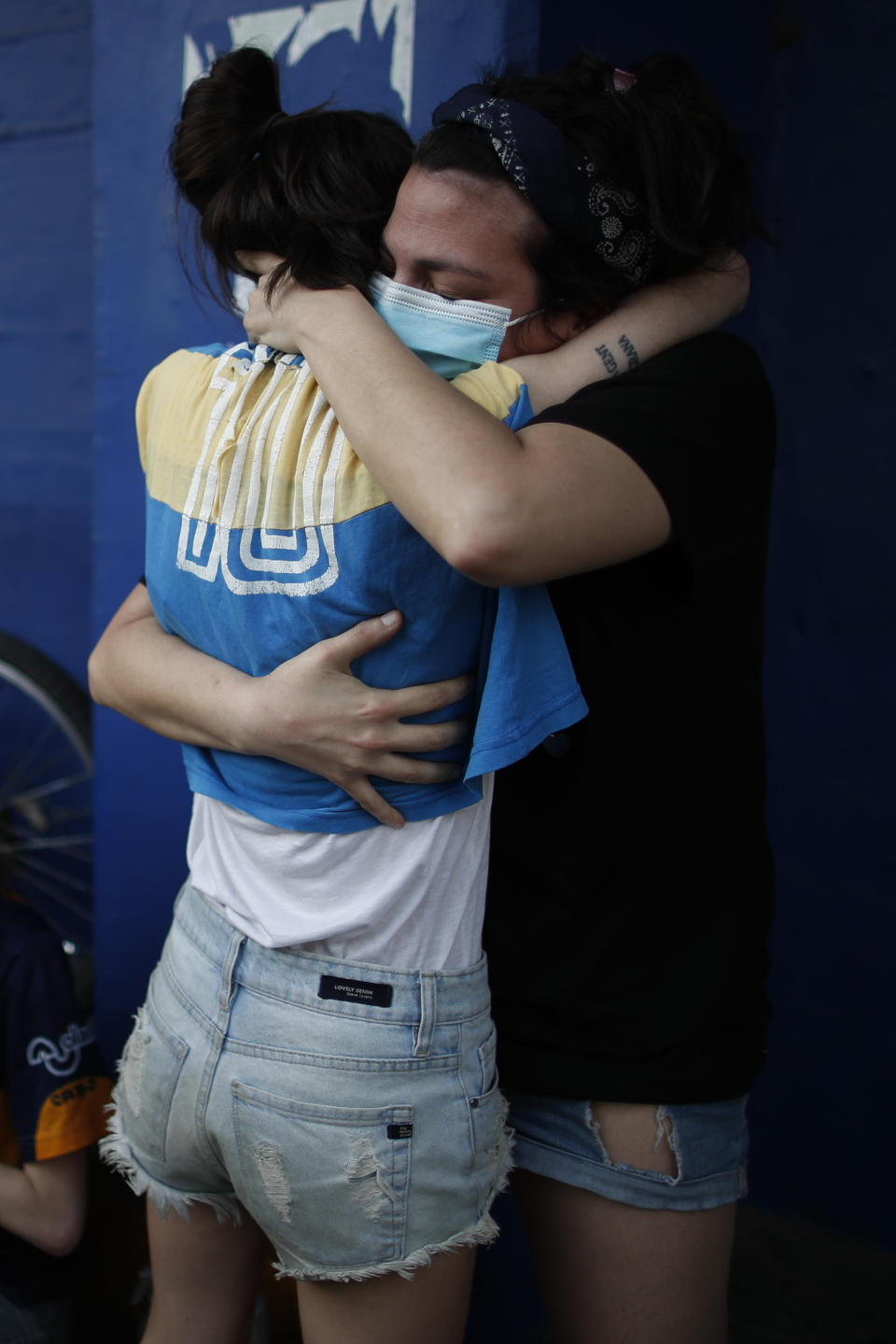 Fans mourn the death of Diego Maradona, at the entrance of the Boca Juniors stadium, known as La Bombomera, in Buenos Aires, Argentina, Wednesday, Nov. 25, 2020. The Argentine soccer great who was among the best players ever and who led his country to the 1986 World Cup title before later struggling with cocaine use and obesity, died from a heart attack on Wednesday at his home in Buenos Aires. He was 60. (AP Photo/Natacha Pisarenko)