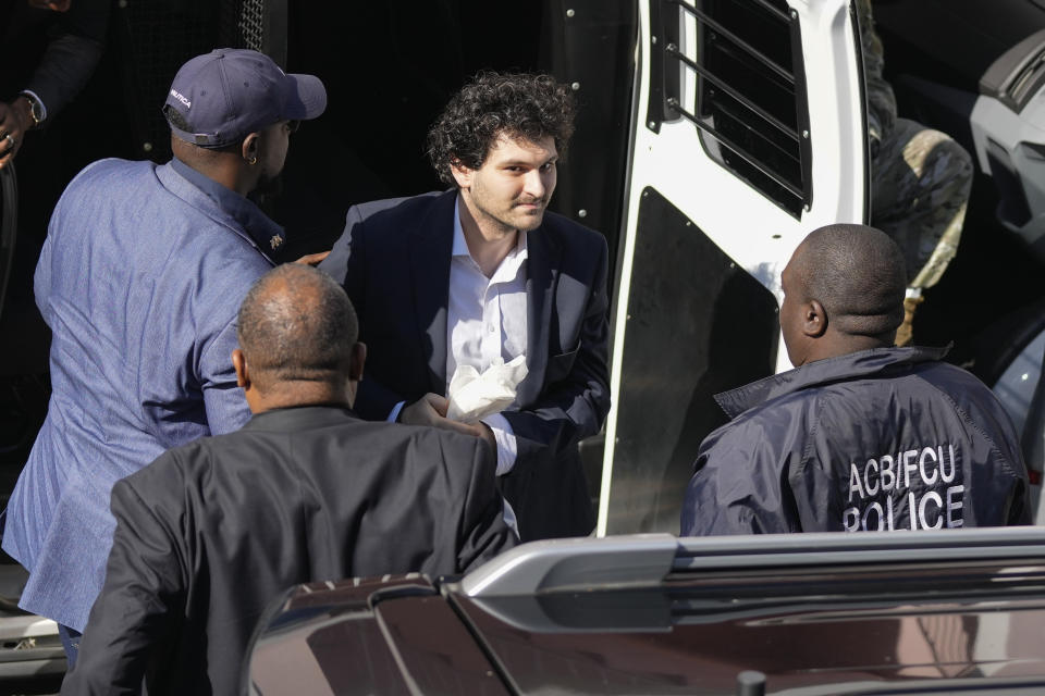 FTX founder Sam Bankman-Fried, center, is escorted from a Corrections Department van as he arrives at the Magistrate Court building for a hearing, in Nassau, Bahamas, Wednesday, Dec. 21, 2022.(AP Photo/Rebecca Blackwell)