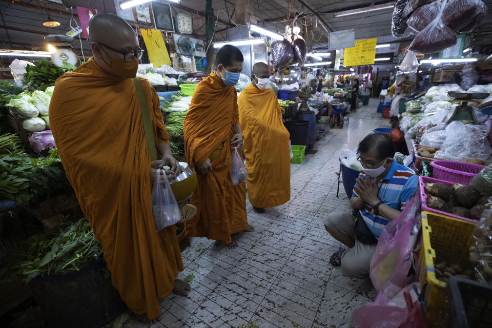 A Thai Buddhist prays after offering food to Thai Buddhist monks as they wear face masks to protect themselves from a new coronavirus in Bangkok, Thailand, Wednesday, March 25, 2020. Thailand's government agreed to declare an emergency to take stricter measures to control the coronavirus outbreak that has infected hundreds of people in the Southeast Asian country. For most people, the new coronavirus causes mild or moderate symptoms, such as fever and cough that clear up in two to three weeks. For some, especially older adults and people with existing health problems, it can cause more severe illness, including pneumonia and death. (AP Photo/Sakchai Lalit)