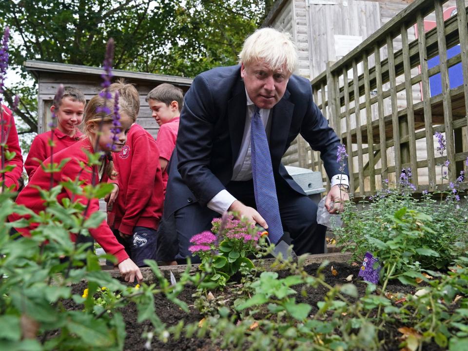 Johnson plants flower bulbs with the school children weeks before the Cop26 climate conference (PA)