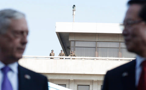  North Korean soldiers (back) look on as US Defense Minister James Mattis (L) and South Korean Defense Minister Song Young-Moo (R) speak to the media at the Joint Security Area (JSA) on the Demilitarized Zone - Credit: EPA