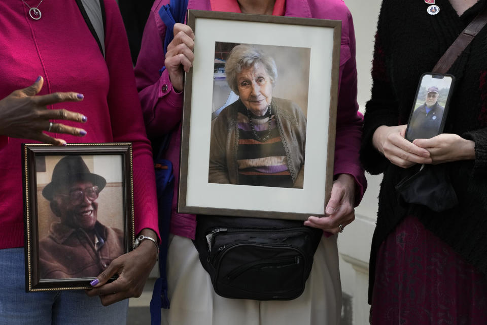 Relatives of those who died during the pandemic gather with photographs of their loved ones outside the opening hearing of Module 2 of the UK Covid 19 Inquiry, in London, Tuesday, Oct. 3, 2023. Bereaved families are coming together to protest the fact that in the module investigating core government decision making during the pandemic, only 1 bereaved family witness has been called to give evidence, out of the over 230,115 families bereaved by Covid 19. (AP Photo/Kirsty Wigglesworth)