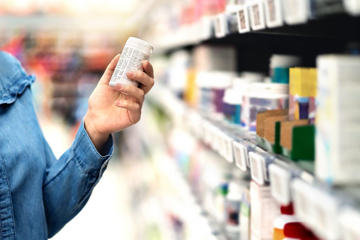 hand holding bottle of supplement pills