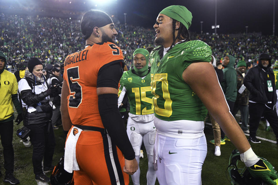 Oregon State quarterback DJ Uiagalelei, left, and Oregon defensive end Matayo Uiagalelei, who are brothers, visit after an NCAA college football game Friday, Nov. 24, 2023, in Eugene, Ore. (AP Photo/Mark Ylen)