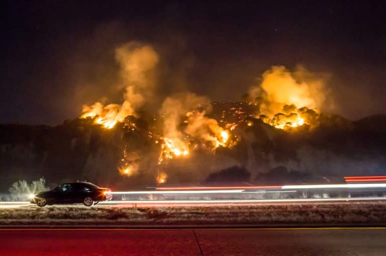 A car drives past as the Thomas Fire burns a hillside south of Casitas Springs, California