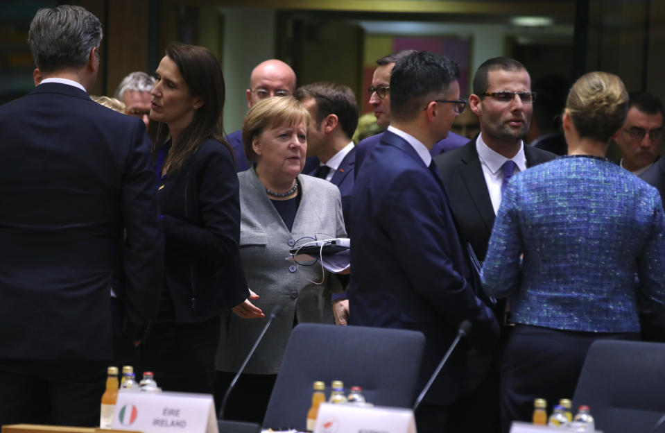 FILE - In this Feb. 21, 2020 file photo, German Chancellor Angela Merkel, center, arrives for a round table meeting at an EU summit in Brussels. European Union leaders are convening by video conference Thursday, March 26, 2020, for their third summit in three weeks, as they battle to contain the spread of the coronavirus. The new coronavirus causes mild or moderate symptoms for most people, but for some, especially older adults and people with existing health problems, it can cause more severe illness or death. (AP Photo/Olivier Matthys, File)