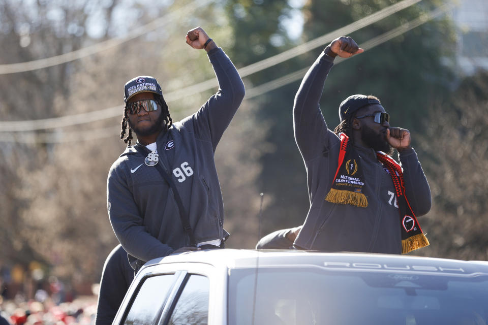 Georgia defensive linemen Zion Logue, left, and Nazir Stackhouse, right, acknowledge the crowd during a parade celebrating the Bulldog's second consecutive NCAA college football national championship, Saturday, Jan. 14, 2023, in Athens, Ga. (AP Photo/Alex Slitz)