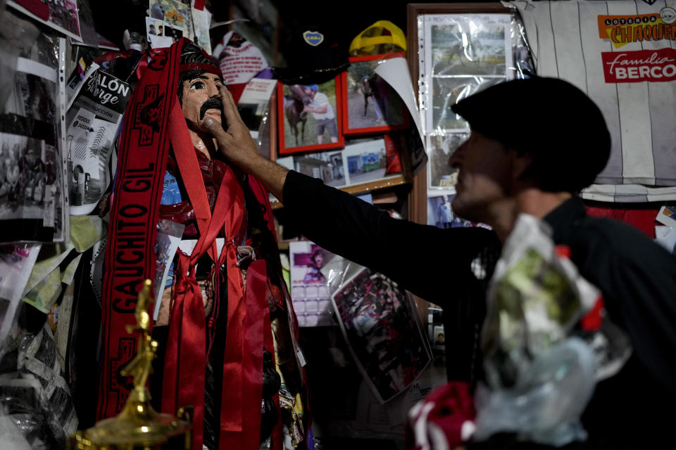 Un hombre toca una representación del santo pagano argentino Gauchito Gil en su santuario en Mercedes, Corrientes, Argentina, el domingo 7 de enero de 2024. Cada 8 de enero, devotos de todo el país visitan ese espacio para pedir o agradecerle por milagros. (AP Foto/Natacha Pisarenko)