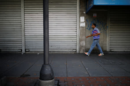 A man walks past closed stores at a commercial area in Caracas, Venezuela August 21, 2018. REUTERS/Carlos Garcia Rawlins