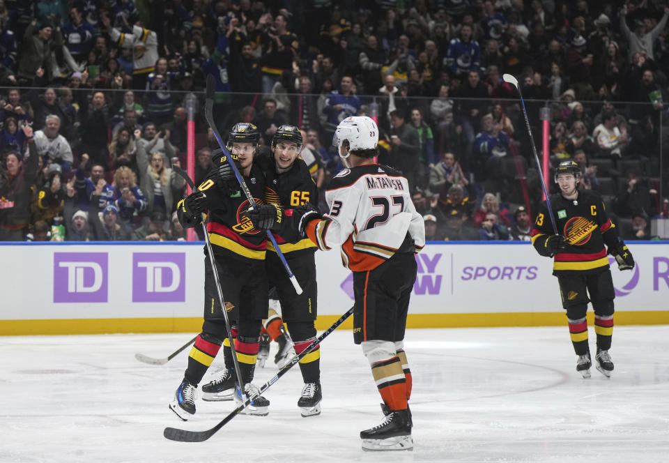 Vancouver Canucks' Elias Pettersson, back left, and Ilya Mikheyev (65) celebrate Pettersson's goal as Quinn Hughes, right, skates to join them while Anaheim Ducks' Mason McTavish (23) watches during the third period of an NHL hockey game in Vancouver, on Tuesday, Nov. 28, 2023. (Darryl Dyck/The Canadian Press via AP)