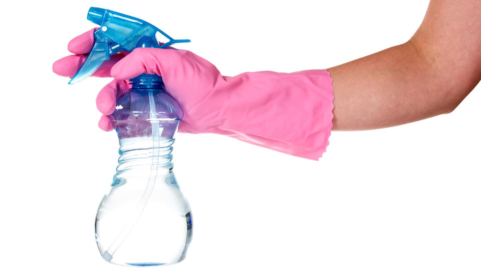 Hand in pink rubber glove holding clear spray bottle (FeaturePics)