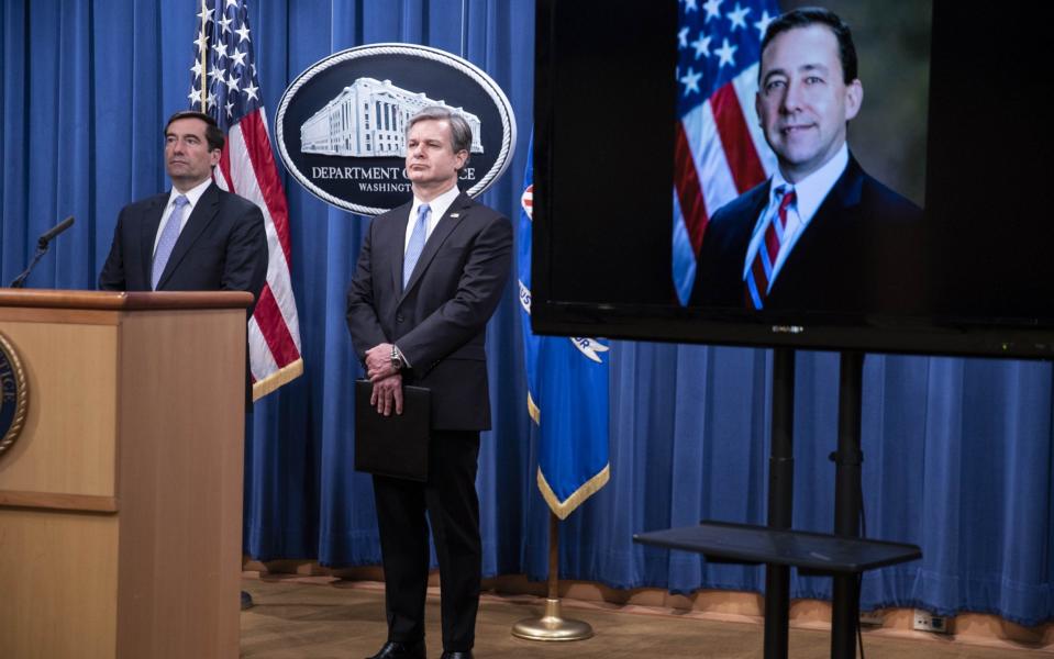 Assistant attorney general for national security John C Demers (left), FBI director Christopher Wray and acting US attorney for the Eastern District of New York Seth DuCharme (on screen) announce the charges at the Department of Justice - Shutterstock