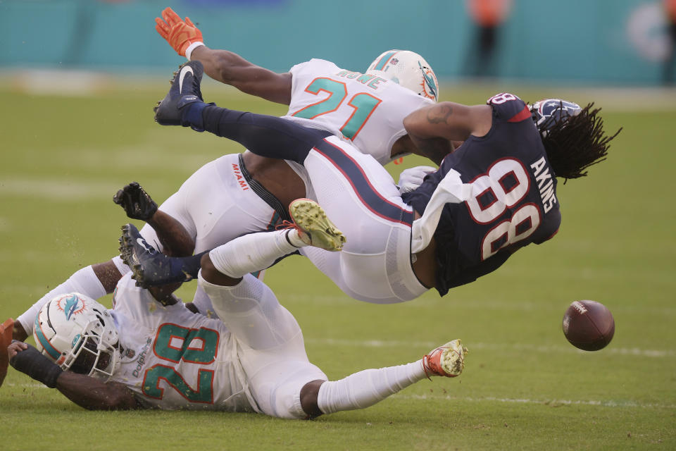 Houston Texans tight end Jordan Akins (88) fumbles the ball after colliding with Miami Dolphins safety Eric Rowe (21) and cornerback Kader Kohou (28) during the first half of an NFL football game, Sunday, Nov. 27, 2022, in Miami Gardens, Fla. The fumble lead to a Miami Dolphins touchdown. (AP Photo/Michael Laughlin)