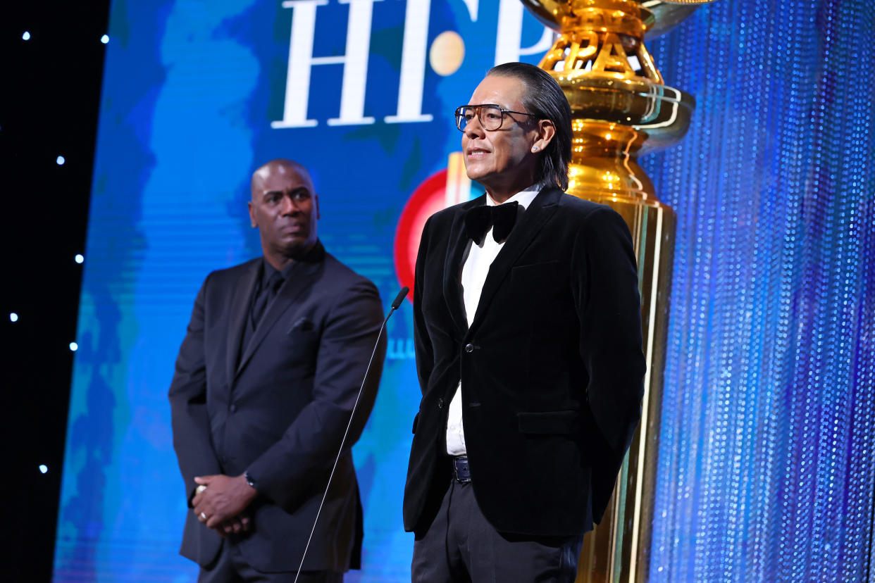 HFPA Chief Diversity Officer Neil Phillips and IllumiNative’s Bird Runningwater speak onstage during the 2022 Golden Globe Awards. - Credit: Getty Images for Hollywood Forei
