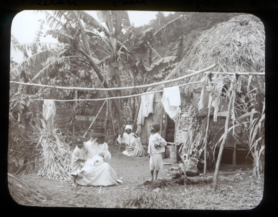 In this 1902 photo provided by York Museums Trust, residents are seen outside their home following explosive eruptions of La Soufrière volcano, in Chateaubelair, St. Vincent. Most of St. Vincent's casualties from the volcano in 1902 were in the east, possibly and partly because workers on large plantations were less able to make an independent decision to flee, according to Jenni Barclay, a volcanology professor. (Tempest Anderson/York Museums Trust via AP)