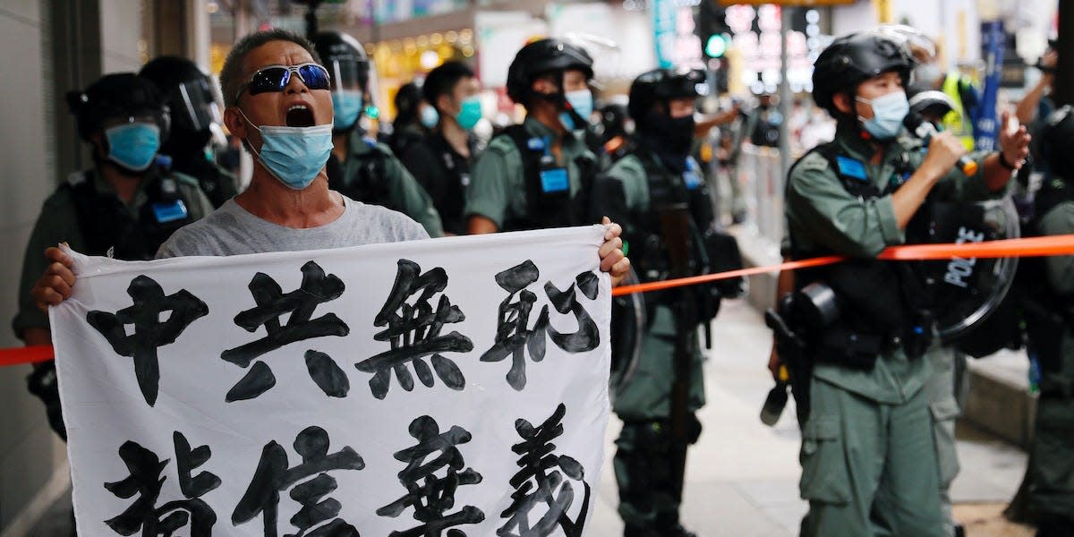 An anti-national security law protester holds a banner reading "Chinese communist party is shameless, break the promises" during a march at the anniversary of Hong Kong's handover to China from Britain in Hong Kong, China July 1, 2020.