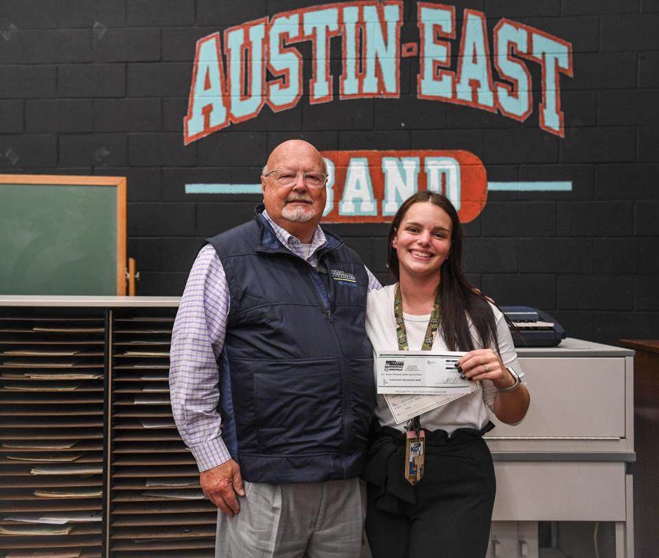 Ray Huffaker (left), owner of Rusty Wallace dealerships, stands next to Alyx Blumenstock (right), Austin East High School's marching band director, as she holds checks totaling $30,000 given to the school by the dealership for new band uniforms in Knoxville, Tuesday, Oct. 24, 2023.