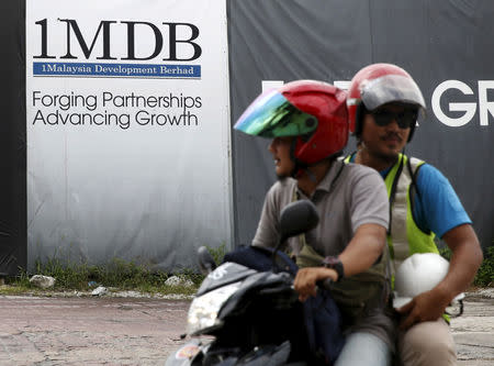 Motorcyclists pass a 1Malaysia Development Berhad (1MDB) billboard at the Tun Razak Exchange development in Kuala Lumpur, Malaysia, February 3, 2016. REUTERS/Olivia Harris/Files