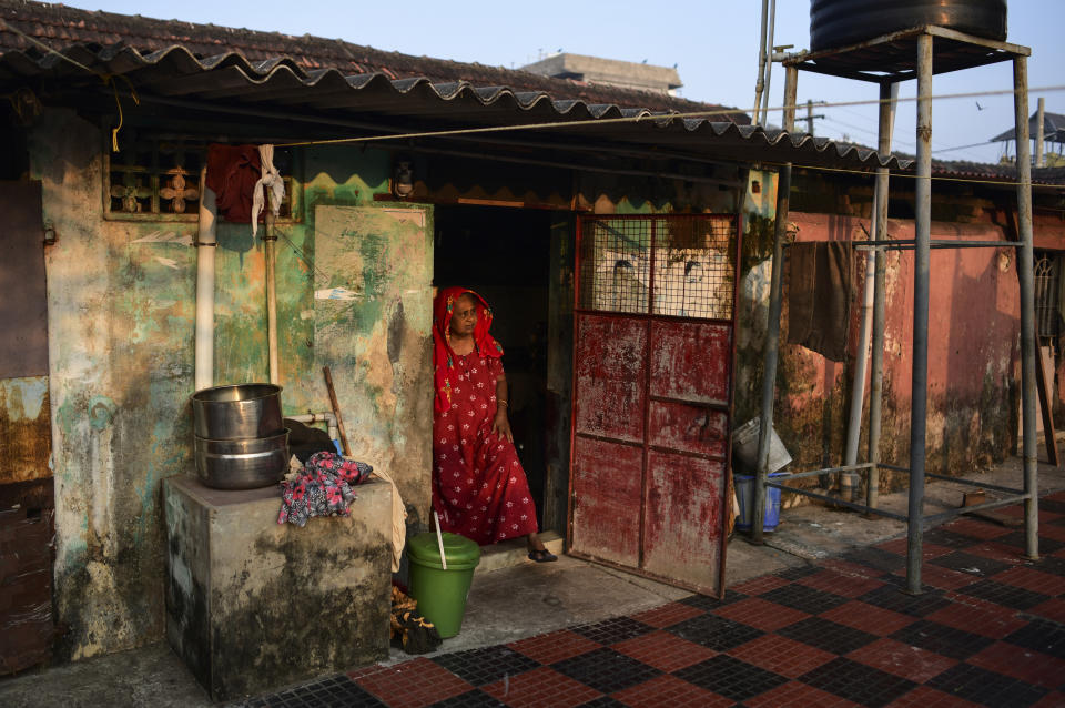 65-year-old Zainaba Ali stands at the entrance of her daughter's asbestos-roofed house where she lives at a colony in the Mattancherry area of Kochi, Kerala, March 6, 2023. The colony is home to mostly low-income families living as 5-6 people in accommodations smaller than 200 square feet per house. Ali spent most of her youth working in the Middle East as a domestic help but has little savings to show for it. She developed arthritis and a slew of other health conditions during those decades of long days and hard work. She was forced to return to India when she was no longer able to work. (AP Photo/ R S Iyer)