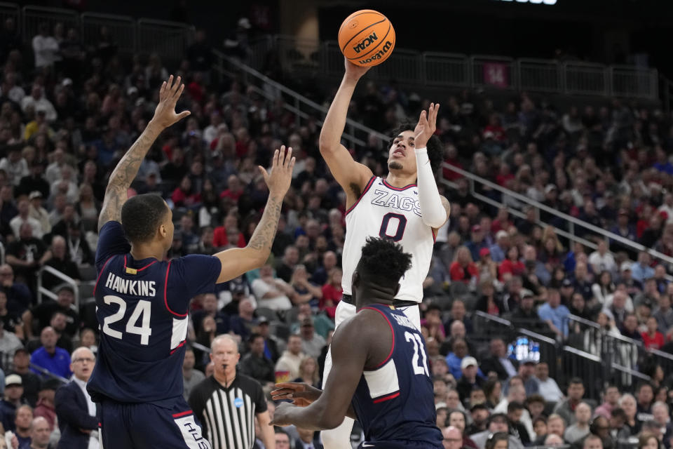 Gonzaga guard Julian Strawther (0) shoots while defended by UConn guard Jordan Hawkins (24) and forward Adama Sanogo in the first half of an Elite 8 college basketball game in the West Region final of the NCAA Tournament, Saturday, March 25, 2023, in Las Vegas. (AP Photo/John Locher)