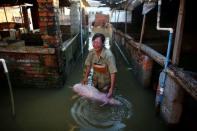 A woman cries as she holds body of a dead pig at a flooded farm in Xiaogan, Hubei Province, China, July 22, 2016. REUTERS/Darley Shen