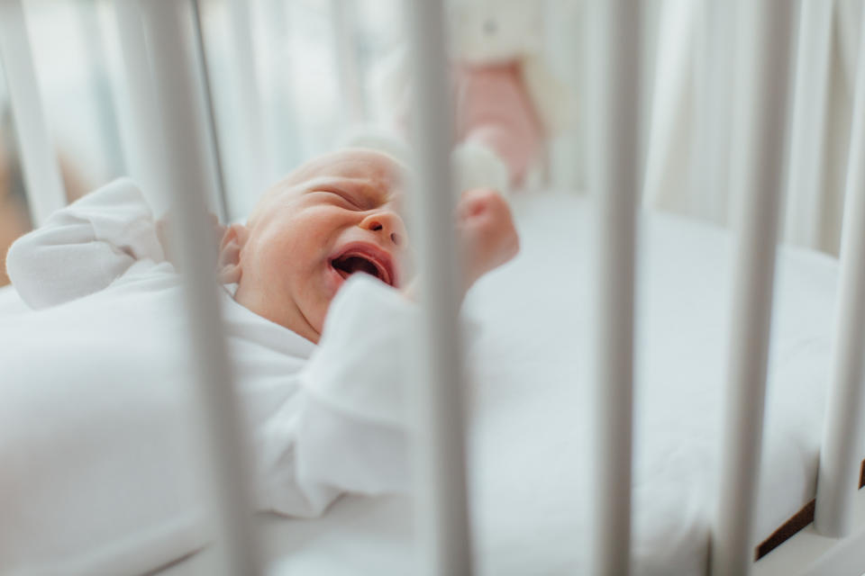 A crying infant in a crib