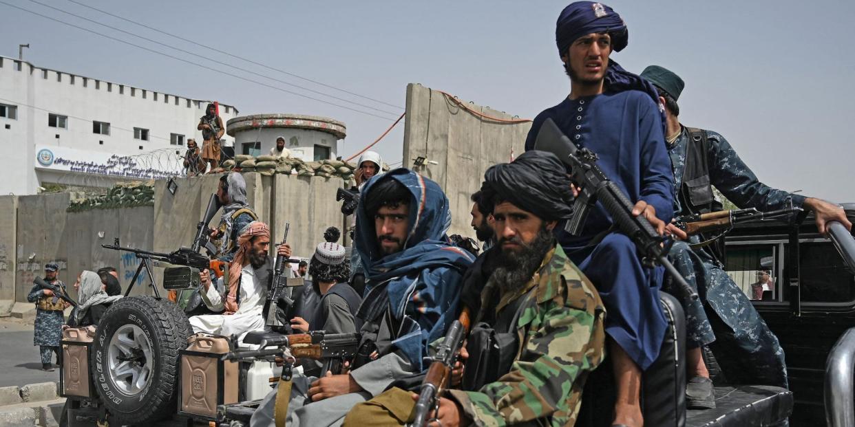 Taliban fighters holding guns on the back of a truck