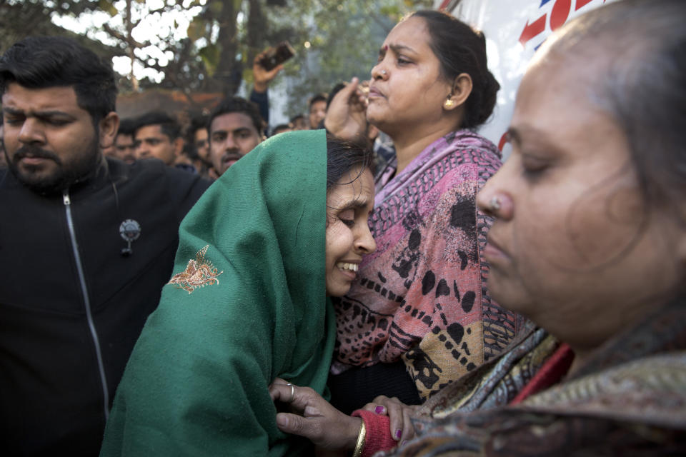 Unidentified relatives gather outside after an early morning fire killed more than a dozen people at a hotel in the Karol Bagh neighborhood of New Delhi, India, Tuesday, Feb.12, 2019. (AP Photo/Manish Swarup)