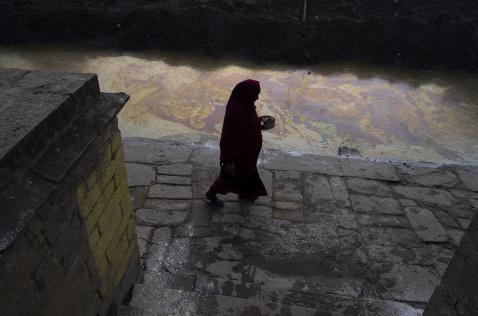 A Hindu devotee arrives to perform rituals by a polluted Hanumante river during Madhav Narayan festival in Bhaktapur, Nepal, Thursday, Jan. 25, 2024. (AP Photo/Niranjan Shrestha)